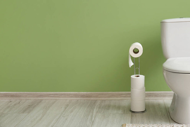 Suporte com rolos de papel e vaso sanitário perto da parede verde - Foto, Imagem