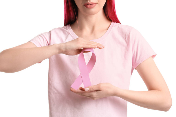 Young woman with pink ribbon isolated on white. Breast cancer awareness concept - Фото, изображение
