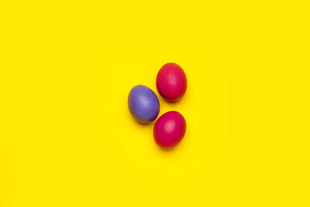 Tres coloridos huevos de Pascua sobre fondo amarillo - Foto, Imagen