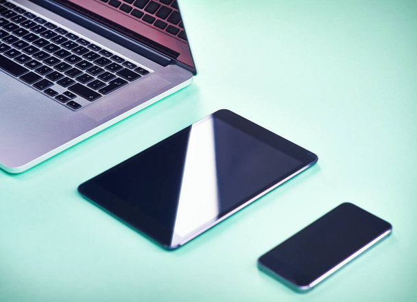 Κομψή σύγχρονη τεχνολογία. Στιγμιότυπο ενός laptop, tablet και smartphone σε πράσινο φόντο. - Φωτογραφία, εικόνα