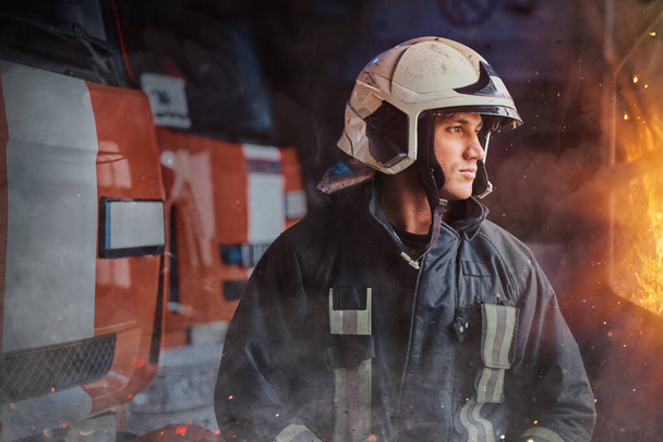 Statečný hasič pózuje kolem požární vůz uvnitř požární stanice - Fotografie, Obrázek