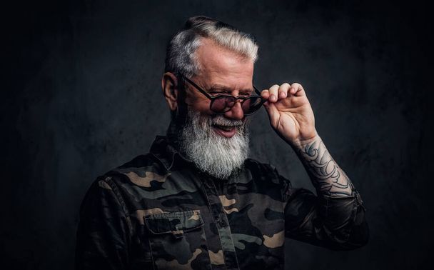 Χαρούμενος γέρος με τατουάζ ντυμένος με ρούχα καμουφλάζ. - Φωτογραφία, εικόνα
