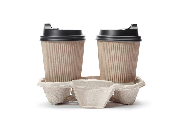 Бумажные кофейные чашки с черными шапками на картонном стенде изолированы на белом фоне. Кофе на вынос. - Фото, изображение