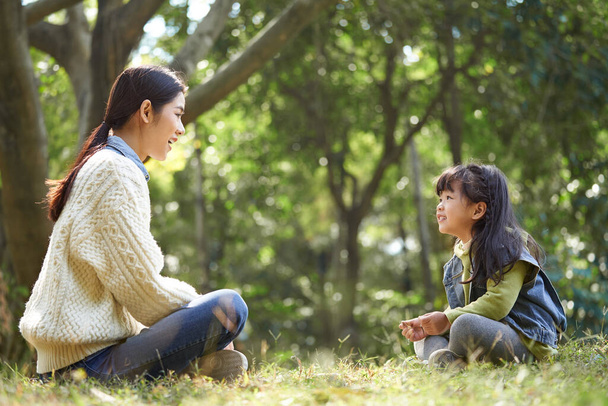 junge asiatische Mutter und Tochter genießen ein Gespräch im Freien im Stadtpark - Foto, Bild