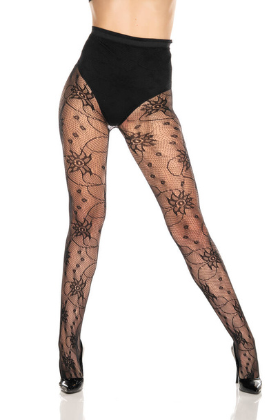 jolies jambes féminines en bas résille et talons hauts noirs sur fond blanc - Photo, image