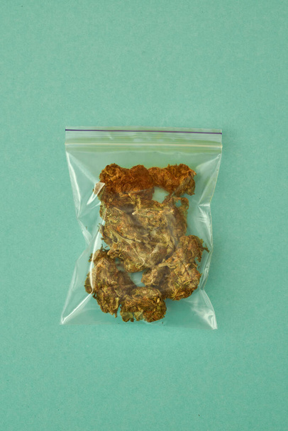 Package with dry marijuana on green background - Foto, afbeelding