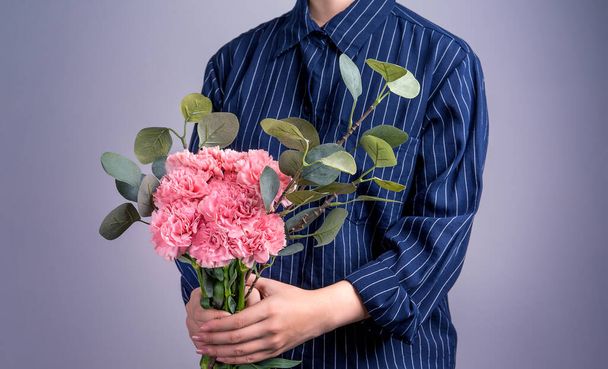 Young girl in dark blue striped shirt giving bunch of handmade beautiful blooming baby pink color carnations as a gift for mothers day concept, close up, copy space, clipping path - Foto, immagini