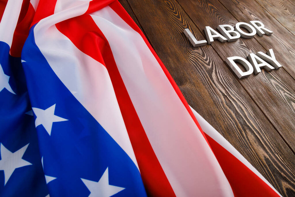 szavak munkanap fektetett ezüst fém betűkkel fa felületen gyűrött amerikai zászló a bal oldalon - Fotó, kép