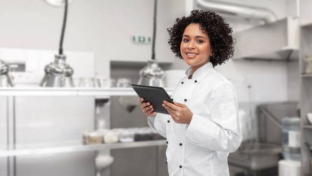 smiling female chef showing tablet pc on kitchen - Foto, Imagem