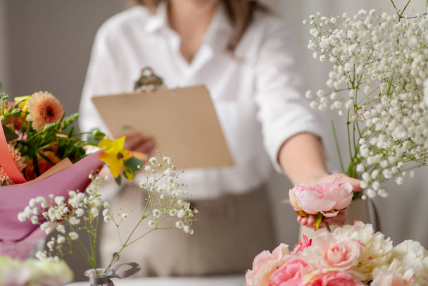 happy woman with clipboard and flowers at studio - Zdjęcie, obraz