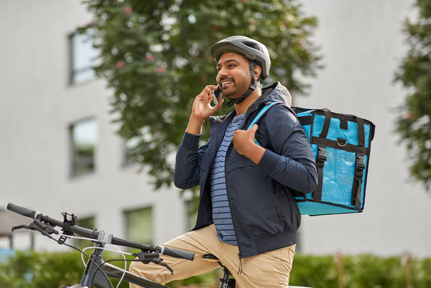 food delivery man with bag calling on smartphone - Fotó, kép