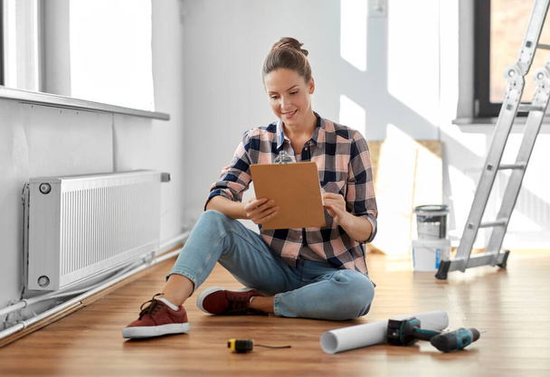 woman with clipboard sitting on floor at home - Photo, Image