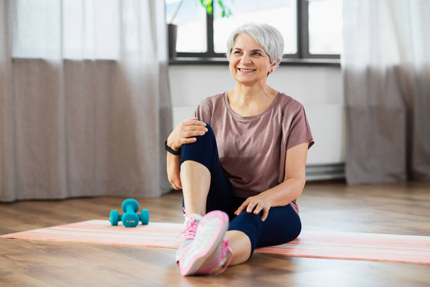 smiling senior woman exercising on mat at home - 写真・画像