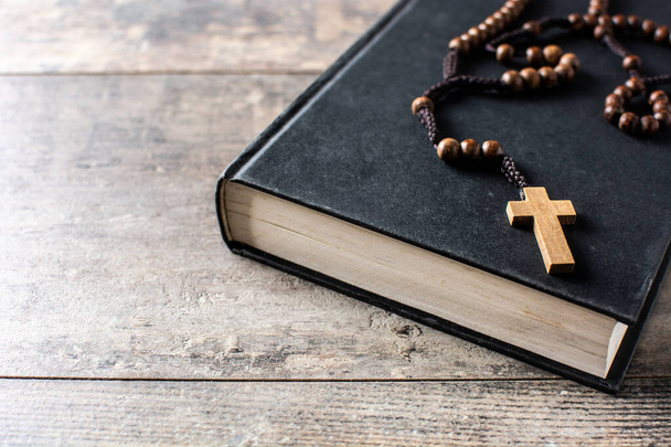 Rosary catholic cross on Holy Bible on wooden table. Copy space - 写真・画像
