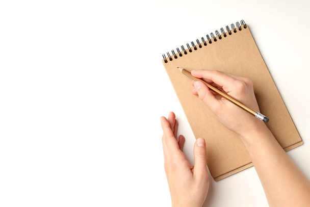 Female hands write in craft notebook on white background - Foto, Imagen