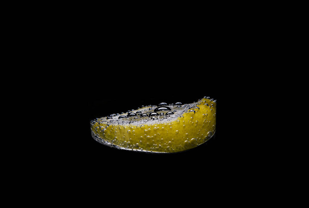 žlutý citron s kapkami vody na černém - Fotografie, Obrázek