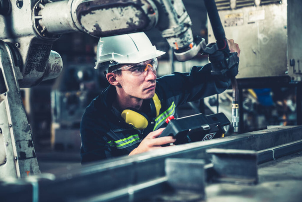 Молодий заводський працівник, що працює з майстерною роботизованою рукою
 - Фото, зображення