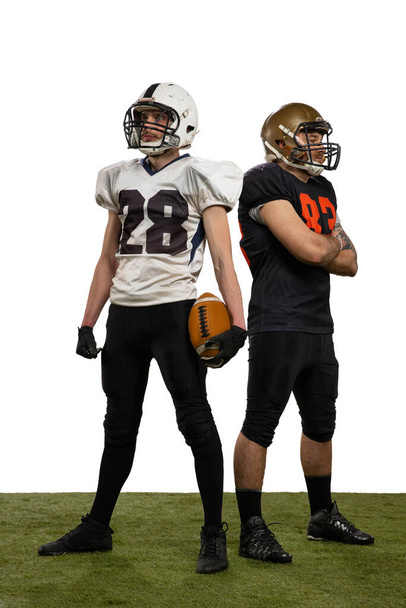 Portrait of two professional american football players in sports uniform and helmets equipment posing isolated on white background. - Foto, Imagen