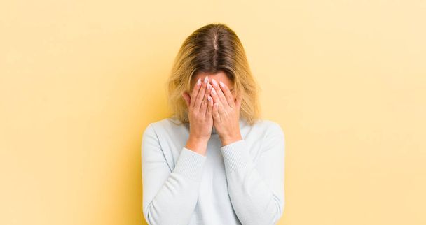 blonde caucasian woman feeling sad, frustrated, nervous and depressed, covering face with both hands, crying - Foto, immagini