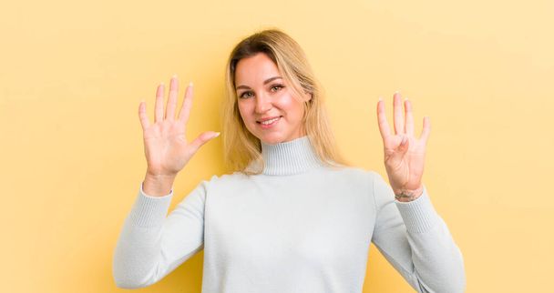blonde caucasian woman smiling and looking friendly, showing number nine or ninth with hand forward, counting down - Fotoğraf, Görsel