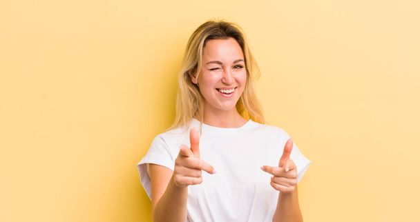 blonde caucasian woman feeling happy, cool, satisfied, relaxed and successful, pointing at camera, choosing you - Фото, изображение