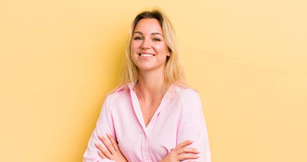 blonde caucasian woman laughing happily with arms crossed, with a relaxed, positive and satisfied pose - Фото, изображение