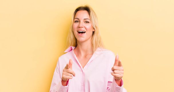 blonde caucasian woman smiling with a positive, successful, happy attitude pointing to the camera, making gun sign with hands - Foto, immagini