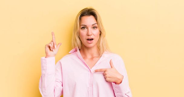 blonde caucasian woman feeling proud and surprised, pointing to self confidently, feeling like successful number one - Photo, image