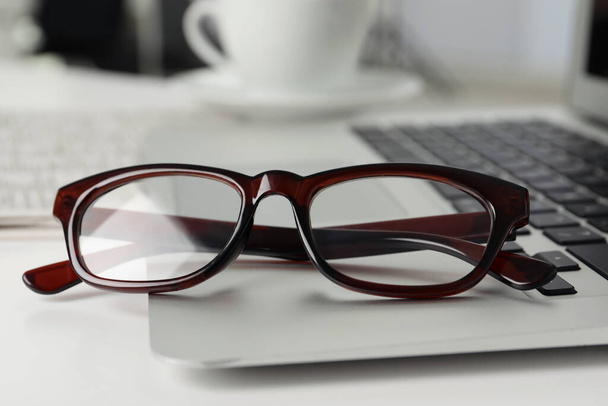 Modern laptop and glasses on white table, closeup - Фото, зображення