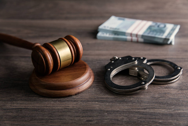 Law gavel with money and handcuffs on wooden table backgroun - Φωτογραφία, εικόνα