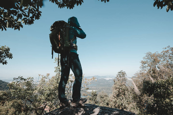Successful hiker taking photo on sunrise mountain top cliff edge - Фото, изображение