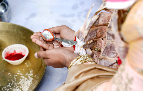 Indický ženich vykonávající rituály držící rýži ve svých mehndi navržených rukou během svatebního obřadu. - Fotografie, Obrázek