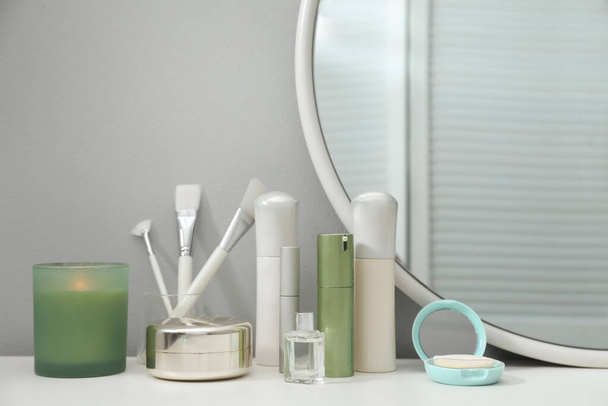 Stylish round mirror on dressing table with cosmetic products - Zdjęcie, obraz