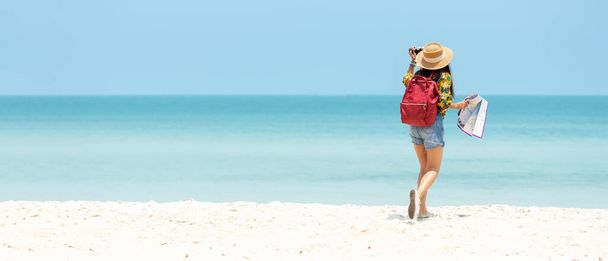 Щаслива мандрівниця і туристка, молоді жінки подорожують літом на пляжі. Азійці, які тримають камеру, роблять фото і відпочивають на відкритому повітрі та подорожують у відпустку. Копіювальний простір для знамена - Фото, зображення