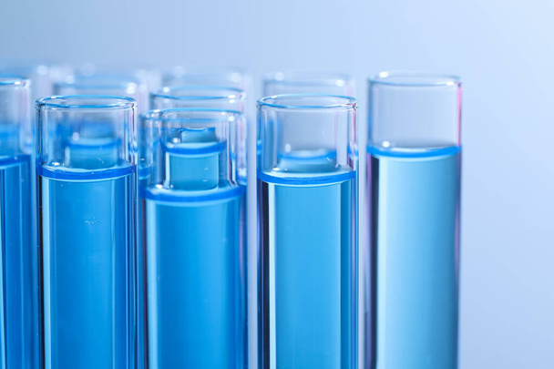 Test tubes with reagents on light blue background, closeup. Laboratory analysis - 写真・画像
