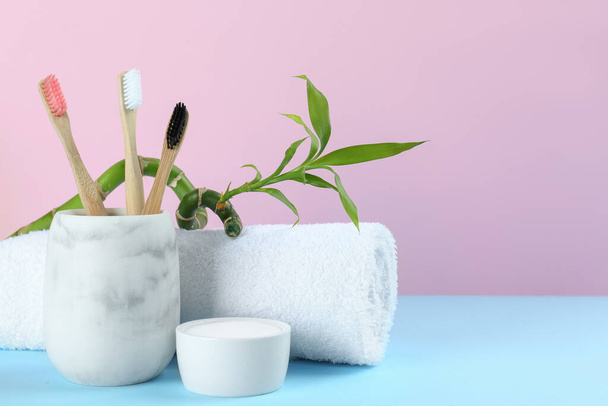 Bamboo toothbrushes, towel and bowl of baking soda on light blue table against pink background, space for text - Fotografie, Obrázek