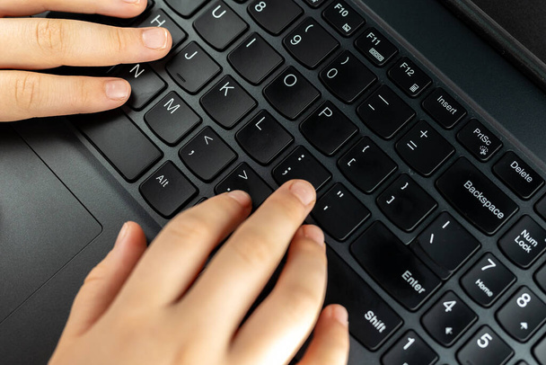 Mladá dívka píše na klávesnici. Riskantní chování dětí na internetu. - Fotografie, Obrázek