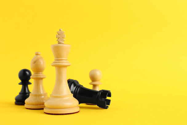 Different chess pieces on yellow background. Space for text - Zdjęcie, obraz