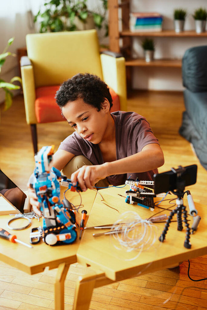 Um pequeno engenheiro a construir um robô em casa. - Foto, Imagem