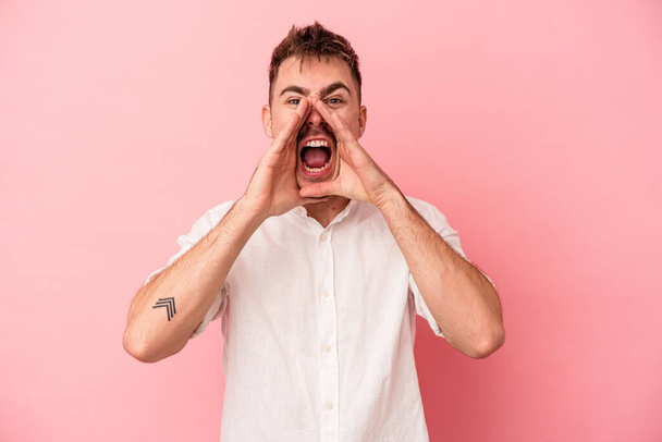 Young caucasian man isolated on pink background shouting excited to front. - Photo, Image