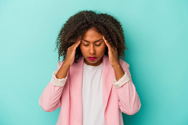 Joven mujer afroamericana con el pelo rizado aislado sobre fondo azul tocando las sienes y teniendo dolor de cabeza. - Foto, Imagen