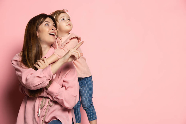 Dreams. Portrait of young woman and little girl, mother and daughter isolated on pink studio background. Mothers Day celebration. Concept of family, childhood, motherhood - Fotoğraf, Görsel