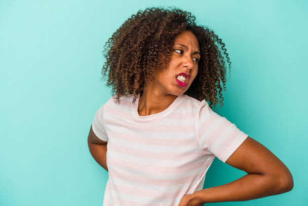 Junge afrikanisch-amerikanische Frau mit lockigem Haar isoliert auf blauem Hintergrund leidet unter Rückenschmerzen. - Foto, Bild