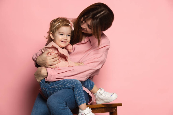 Support and care. Young woman and little girl, mother and daughter isolated on pink studio background. Mothers Day celebration. Concept of family, childhood, motherhood - Fotografie, Obrázek
