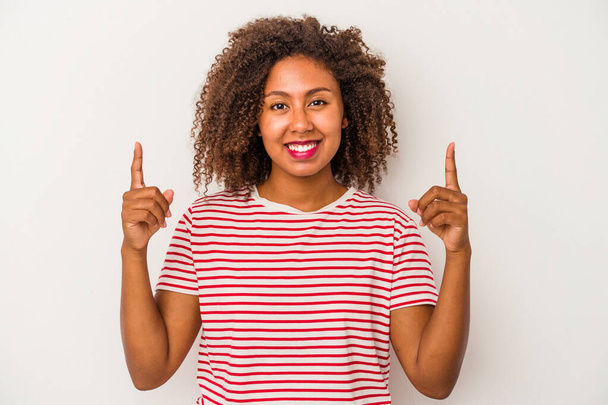 白い背景に巻き毛のある若いアフリカ系アメリカ人女性は、両方の前の指が空白のスペースを示すことを示しています. - 写真・画像