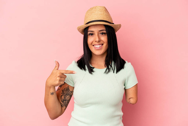 Mujer caucásica joven con un brazo que lleva un sombrero de verano aislado en el fondo rosa persona señalando a mano a un espacio de copia de la camisa, orgulloso y seguro - Foto, Imagen
