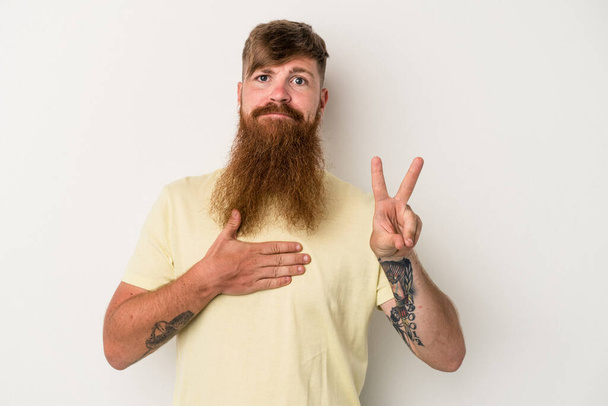 Young caucasian ginger man with long beard isolated on white background taking an oath, putting hand on chest. - Foto, Imagem