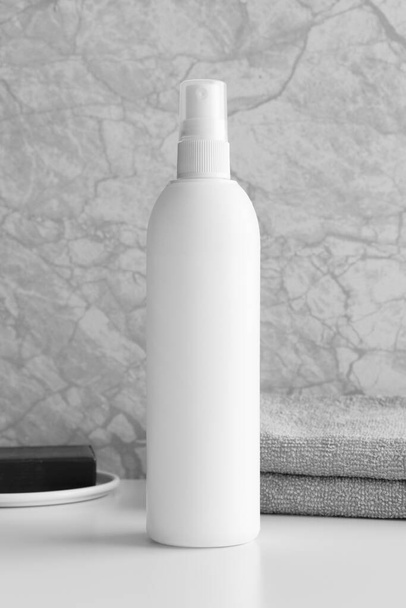 Weiße Sprühflaschen-Attrappe mit Seife und Handtuch auf dem weißen Tisch. - Foto, Bild