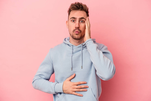 Young caucasian man isolated on pink background blows cheeks, has tired expression. Facial expression concept. - Фото, зображення