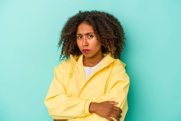Giovane donna afroamericana con i capelli ricci isolati su sfondo blu sospettoso, incerto, esaminando voi. - Foto, immagini